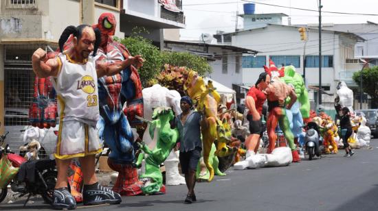 Un hombre carga varios monigotes en una calle del suburbio de Guayaquil, el 28 de diciembre de 2023.