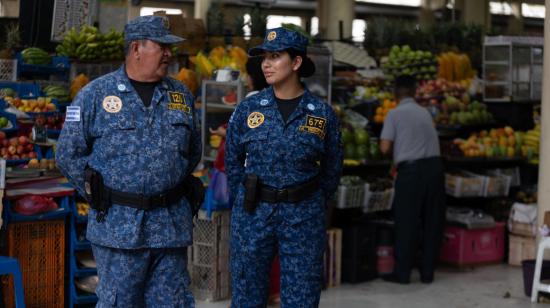 Dos agentes metropolitanos en un mercado municipal de Guayaquil, que funciona con normalidad, el 10 de enero de 2024.