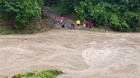 Varios habitante de Pedernales junto al río Beche, que se desbordó debido a las lluvias de las últimas horas, el 30 de enero de 2024.