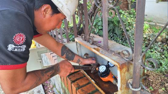 Un funcionario de la empresa de agua potable de Cuenca instala un medidor.