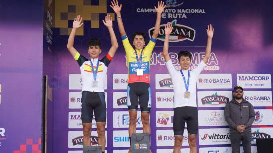 Mateo Ramírez (medio) levanta sus brazos en el podio del Campeonato Nacional de Ciclismo, en Guano, el 2 de febrero de 2024.