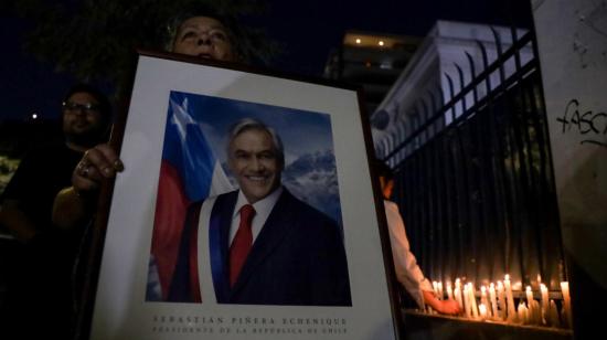 Una mujer sostiene un retrato del fallecido expresidente, Sebastián Piñera, en los exteriores del palacio de gobierno en Santiago de Chile, el 6 de febrero de 2024.