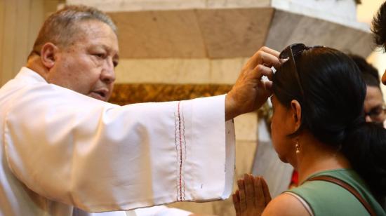 Un sacerdote impone la ceniza a feligreses de la iglesia San Francisco, en Guayaquil.