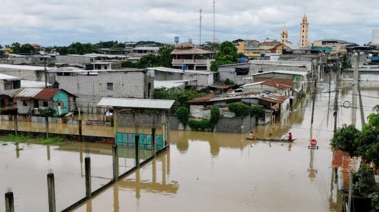 Hombres en una canoa transitan por una calle del barrio Morochal, en Santa Lucía (Guayas), donde tres barrios quedaron totalmente bajo el agua.