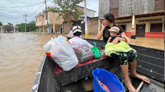 Una mujer y su niño rescatada en una canoa en Chone el 21 de febrero de 2024.