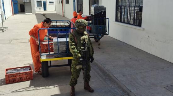 Bajo custodia militar, los presos movilizan la comida que se repartirá en los pabellones del CRS Cotopaxi.