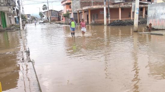 Habitantes del cantón Chone, en Manabí, caminan por las calles inundadas el 23 de febrero de 2024. 