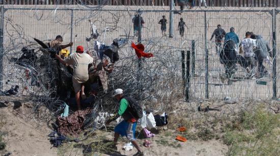 Migrantes cruzan una alambrada de navajas y púas, en la frontera que divide a México de los Estados Unidos, el 14 de marzo de 2024, en Ciudad Juárez (México). 