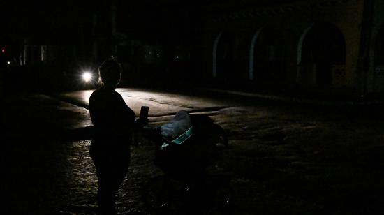 Una mujer empuja un cochecito por una calle oscura durante un apagón en Bauta, provincia de Artemisa, Cuba.