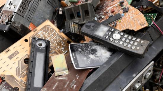 Varios teléfonos celulares y otros dispositivos electrónicos en un vertedero de basura.