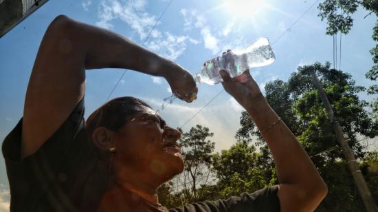 Una mujer se refresca con una botella de agua en Guayaquil. 