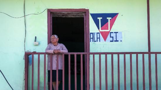 Una mujer se asoma por un balcón en la población de Alausí.