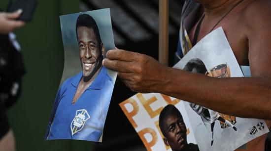 Un vendedor muestra carteles de la leyenda del fútbol brasileño Pelé afuera del estadio Urbano Caldeira, donde se llevó a cabo un velorio en su honor, el 2 de enero de 2023.