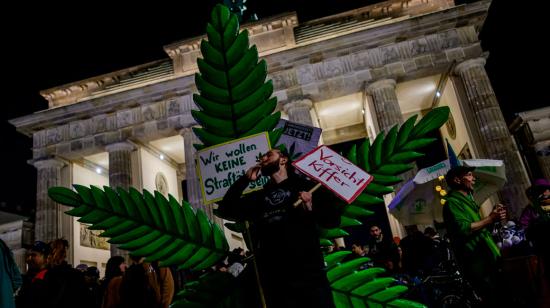 Un ciudadano fuma frente a una planta gigante de marihuana simulada durante una manifestación frente a la Puerta de Brandenburgo, en Berlín.