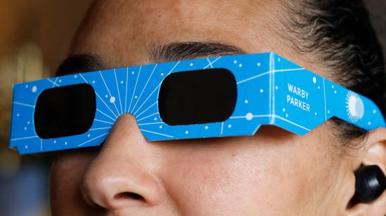 Una mujer utiliza unas gafas de eclipse, recomendadas para observar estos fenómenos para evitar riesgos a la salud.