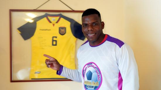 Geovanny 'Cuchara' Caicedo posa junto a una de las camisetas de su hijo Djorkaeff en la sala de su casa el 3 de abril de 2024.