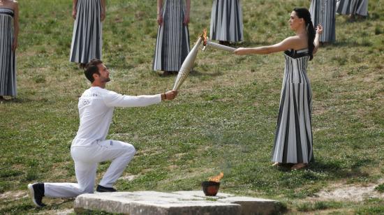 La actriz griega Mary Mina, en el papel de la Alta Sacerdotisa, pasa la llama olímpica al primer campeón olímpico griego de remo Stefanos Ntouskos, durante la Ceremonia de la Llama Olímpica de los Juegos Olímpicos de París 2024, el 16 de abril de 2024.