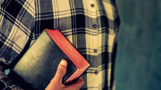 Imagen referencial de una persona con un libro religioso.