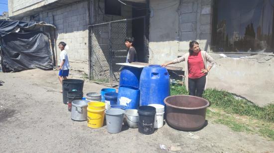 Cristina González junto a baldes de agua, a la espera de un tanquero, el 24 de abril de 2024, en Quito.