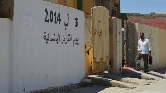 Un hombre camina por la calle en Sinyar, en el norte de Irak, el 1 de agosto de 2019 frente a un muro en el que se puede leer en árabe "3 de Agosto, el día en que se extinguió la humanidad". 