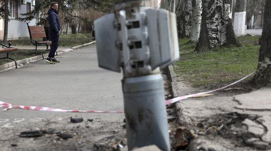 Un hombre pasa junto a una sección de cola sin explotar de un cohete de 300 mm que parece contener bombas de racimo lanzadas desde un lanzacohetes múltiple BM-30 Smerch incrustado en el suelo después de un bombardeo en Lysychansk, región de Lugansk, el 11 de abril de 2022.