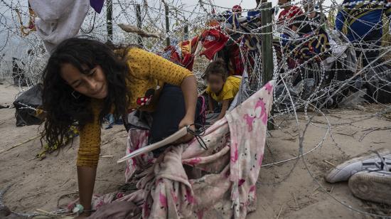 Migrantes de Venezuela se arrastran a través de un agujero en el alambre de púas para cruzar a Eagle Pass, Texas, el 25 de septiembre de 2023.