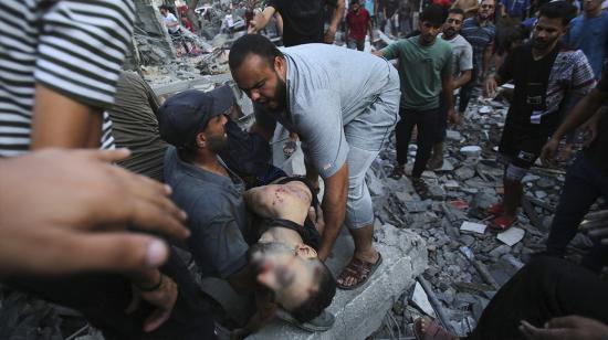 La gente evacua el cuerpo de un hombre del lugar de un ataque israelí en la ciudad de Gaza el 10 de octubre de 2023. Israel dijo que recuperó las áreas fronterizas de Gaza de manos de Hamás cuando el número de muertos en la guerra superó los 3.000 el 10 de octubre, el cuarto día de agotadores combates desde que los islamistas lanzaron un ataque sorpresa.