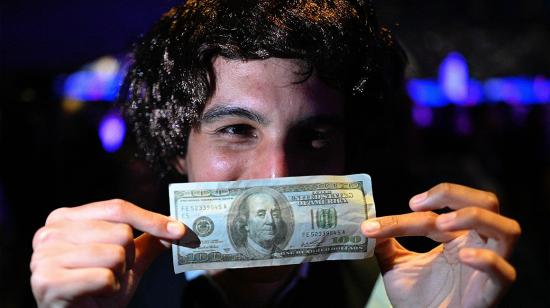 Un partidario del congresista argentino y candidato presidencial de la alianza La Libertad Avanza, Javier Milei, vestido como él, sostiene un billete de 100 dólares durante el cierre de su campaña en el Movistar Arena de Buenos Aires el 18 de octubre de 2023, antes de las elecciones presidenciales de Argentina. elecciones que se celebrarán el 22 de octubre.