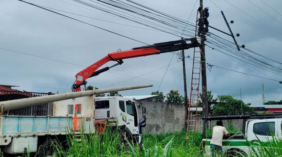 Funcionarios de CNEL realizan trabajos en un poste de luz.