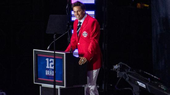 Tom Brady, usa su chaqueta roja de incorporación al Salón de la Fama de los Patriots, mientras habla durante la ceremonia de incorporación, el 12 de junio de 2024.