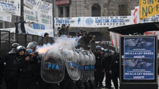 La policía antidisturbios disparan gases lacrimógenos junto a carteles contra las reformas del presidente Javier Milei.