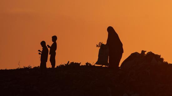 Los palestinos desplazados se reúnen al atardecer en una colina de basura, 23 de junio de 2024.