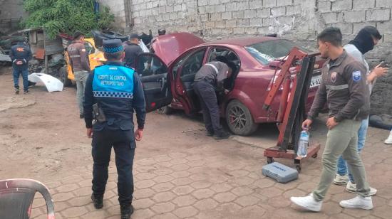 Funcionarios revisan un carro hallado en una mecánica de Quito.