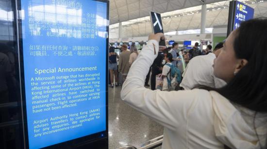 Una mujer toma fotografías a un anuncio sobre el fallo de Microsoft en un aeropuerto de Hong Kong, el 19 de julio de 2024.