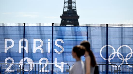 Dos mujeres pasan junto a la Torre Eiffel parcialmente oculta por una valla, antes de los Juegos Olímpicos de París, el 19 de julio de 2024.