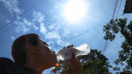 Una mujer se hidrata ante el intenso sol en Ecuador.