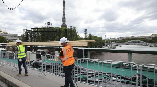 Varios operarios pasan ante el río Sena de París, este martes. El Sena será el escenario elegido para la ceremonia de inauguración de los Juegos Olímpicos el próximo viernes 26 de Julio.