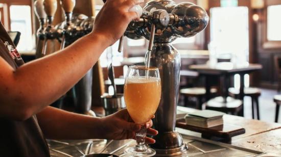 Bartender cirviendo una cerveza de barril.