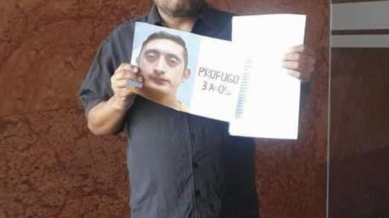 Una persona sostiene una foto de Jonathan Falcón, uno de los más buscados de Ecuador por femicidio.