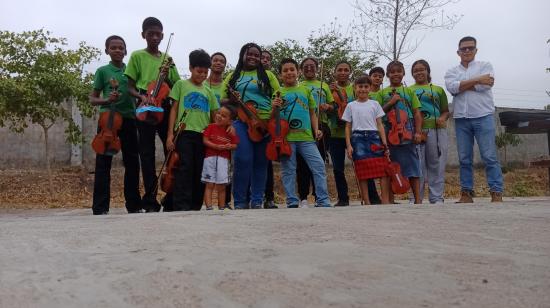 El profesor de música Henry Merchán, de 37 años, posa con uno de los grupos actuales de sus alumnos de violín en Socio Vivienda, al noroeste de Guayaquil.