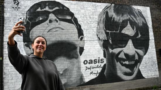 Una fan se toma una 'selfie' frente a un mural de los hermanos Liam and Noel Gallagher, de la banda Oasis, en Manchester, Inglaterra.