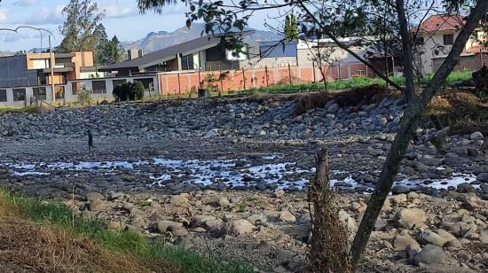 Un adolescente juega entre las piedras del río Tomebamba, en Cuenca, ante la escasa agua debido a la sequía hidrológica.