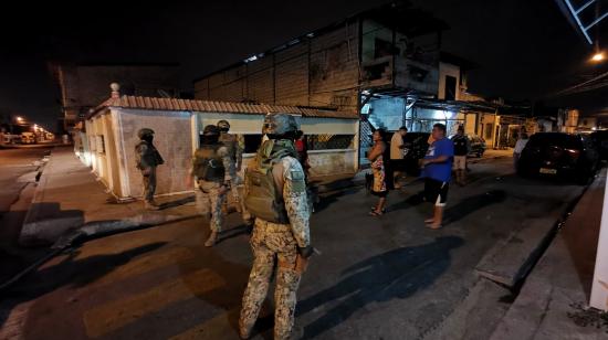 Militares les piden volver a sus domicilios a una docena de vecinos reunidos en la calle a las 22:30 en el sector de la Playita del Guasmo, al sur de Guayaquil, en medio de un toque de queda vigente y de apones que afectaron a buena parte del sector la noche del 18 de septiembre de 2024.