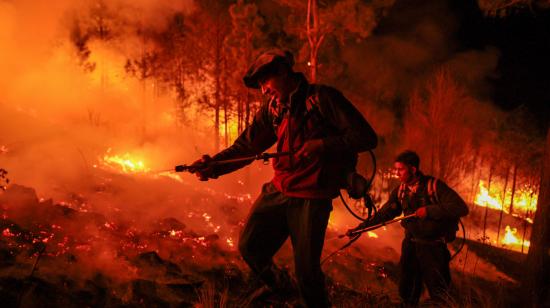 Dos hombres parte de un grupo de bomberos y vecinos autogestionados combaten un incendio forestal el 23 de septiembre de 2024, en Intiyaco, provincia de Córdoba (Argentina).