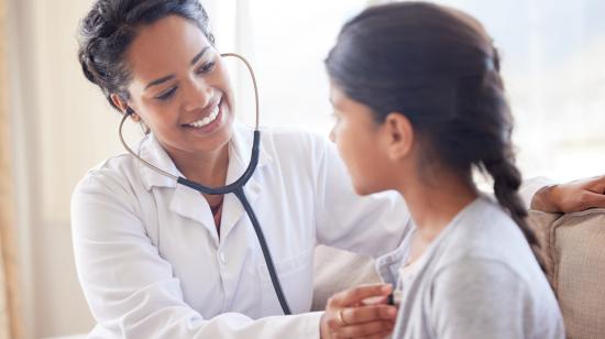 Médico examinando a una niña con un estetoscopio.