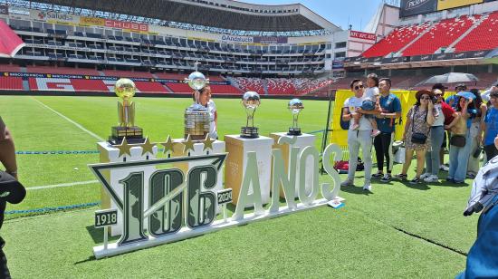 Hinchas de Liga de Quito se toman fotos con las copas internacionales del club, el 19 de octubre de 2024.