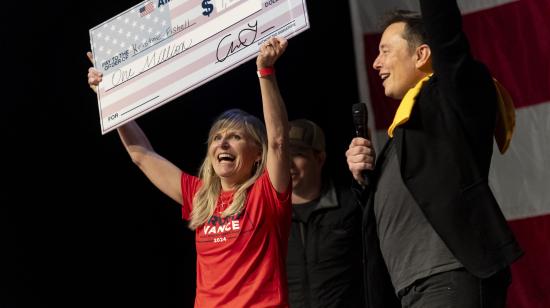 El fundador de SpaceX y Tesla, Elon Musk, entrega un cheque de USD 1 millón  a Kristine Fishell durante un evento de campaña en Harrisburg, Pensilvania, el 20 de octubre de 2024.