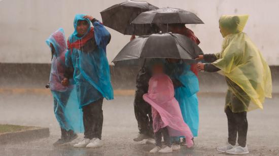 Personas se cubren con plásticos durante una lluvia en Quito.