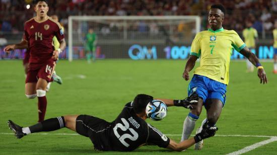 Rafael Romo (abajo) de Venezuela disputa el balón con Vinícius Júnior de Brasil, este jueves 14 de noviembre, durante la Fecha 11 de las Eliminatorias al Mundial 2026.