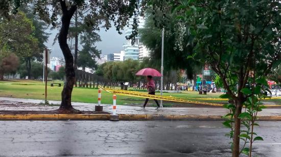 Ciudadana camina con un paraguas por el parque de La Carolina, en el norte de Quito.